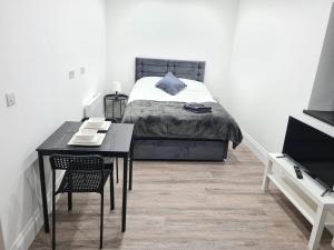 Homestay by BIC Legends 4 في Batley Carr: غرفة نوم بسرير وطاولة سوداء وكرسي