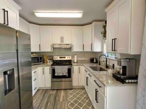 a kitchen with white cabinets and stainless steel appliances at Donna’s Charm: 3 BR/king-suite/pools/golf in Daphne