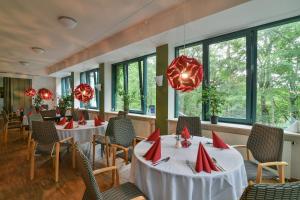 ein Restaurant mit weißen Tischen, Stühlen und roten Servietten in der Unterkunft Luisenburg Resort in Wunsiedel