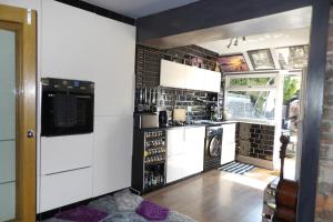 a kitchen with white cabinets and a black tile wall at Aigas in Glasgow