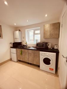 a kitchen with a washing machine and a microwave at Large and comfy studio flat C near Heathrow in New Bedfont