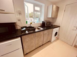 a kitchen with a sink and a microwave at Large and comfy studio flat C near Heathrow in New Bedfont