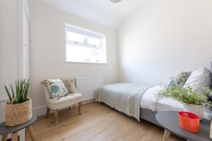 ein Schlafzimmer mit einem Bett, einem Stuhl und einem Fenster in der Unterkunft Charming Elegance at The Pontcanna Pearl - Prime Location with Comfort and Style in Cardiff