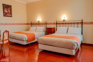 two beds in a room with wood floors at Hostal Colonial Potosi in Potosí