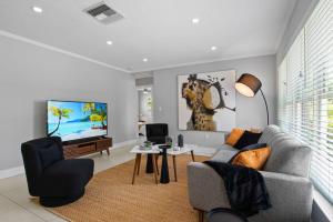 ein Wohnzimmer mit einem Sofa, Stühlen und einem TV in der Unterkunft Coconut Cabana in Fort Lauderdale
