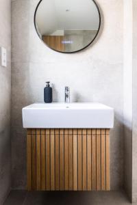 La salle de bains est pourvue d'un lavabo blanc et d'un miroir. dans l'établissement Charming Elegance at The Pontcanna Pearl - Prime Location with Comfort and Style, à Cardiff