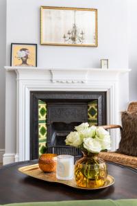 a living room with a fireplace and a table with a vase of flowers at Charming Elegance at The Pontcanna Pearl - Prime Location with Comfort and Style in Cardiff