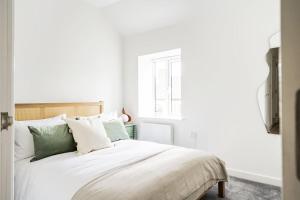 um quarto com uma cama branca com almofadas verdes e brancas em Newport Ship's Nook: Cozy Hideaway em Newport