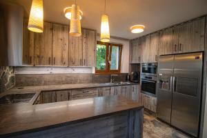 a kitchen with wooden cabinets and a stainless steel refrigerator at Vila Ambiente Donovaly in Donovaly