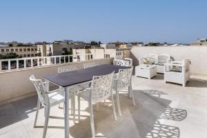 una mesa y sillas en un balcón con vistas en Golden Sunsets Penthouse 10 by Solea, en San Ġwann