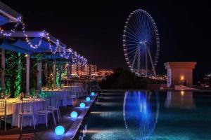 a pool with chairs and a ferris wheel at night at Amazing views Dubai eye & Palm in Dubai