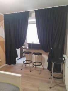 een kamer met zwarte gordijnen en krukken voor een raam bij Victoria Apartment Luxury in Târgu Jiu