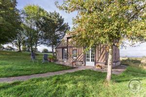 uma cabana de madeira num campo com uma árvore em La Maisonnette em Saint-Pierre-sur-Dives