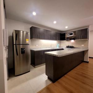 a kitchen with a stainless steel refrigerator and wooden cabinets at La Isabella Deluxe in Mosquera