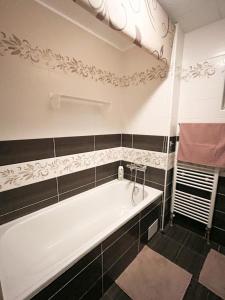 a white bath tub in a bathroom with black tiles at Chalupa Miška in Gôtovany