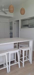 a white kitchen with a white table and benches at Conch Club Cottage in Head of Bay