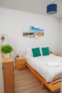 a bedroom with a bed and two night stands and two paintings at Peaceful Oasis By The Sea in Edinburgh
