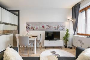 eine Küche und ein Wohnzimmer mit einem Tisch und einem TV in der Unterkunft Zenitude - Casa Vostra - Thonon Centre et Thermes in Thonon-les-Bains