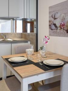 una mesa de comedor con platos y vasos. en Zenitude - Casa Vostra - Thonon Centre et Thermes, en Thonon-les-Bains