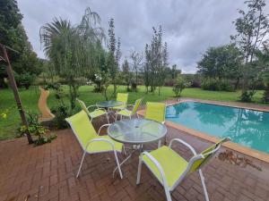 a patio with a table and chairs next to a pool at Riverrun Resort Farmhouse in Tygerfontein