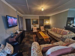 a large living room with couches and a tv at Riverrun Resort Farmhouse in Tygerfontein