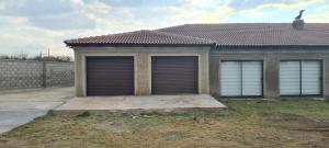 uma casa com duas portas de garagem no quintal em Bonfai Residence em Ermelo