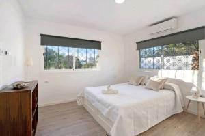 a white bedroom with a bed and two windows at Villa Teide in Santiago del Teide