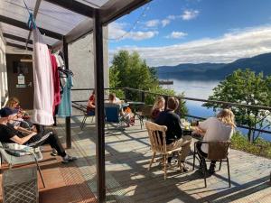 un groupe de personnes assises sur une terrasse avec vue sur l'eau dans l'établissement Loch Ness Lochside Hostel, Over 16s Only, à Invermoriston