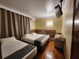 a hotel room with two beds and a television at Aurora Hotel in Ribeirão Preto