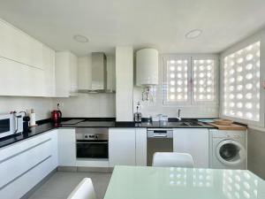 a kitchen with white cabinets and a sink and a dishwasher at Principado Wifi, Airco, Beach and Garden in Benidorm