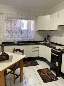 cocina con armarios blancos, mesa y ventana en Sobrado em condomínio fechado, en Carambeí