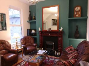 a living room with leather chairs and a fireplace at Cosy Town House in Belfast