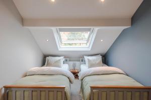 two beds in a attic room with a window at Stunning 3 Bed Duplex Apartment in the heart of West Hampstead in London