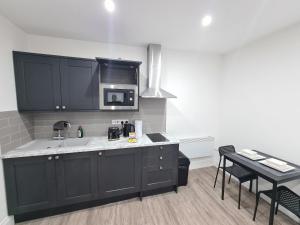 a kitchen with black cabinets and a microwave at Homestay by BIC Legends 5 in Batley Carr