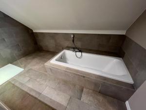 y baño con bañera blanca y suelo de baldosa. en Bolderhuys en Bolderberg