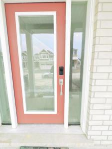 a red door on a house with two windows at Beautiful entire basement with Netflix in Stittsville