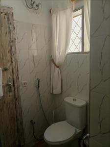 baño con aseo blanco y ventana en Sophia house, en Malindi