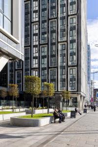 利物浦的住宿－Premium Apartments at Copper House in Liverpool City Centre，坐在高楼前长椅上的人