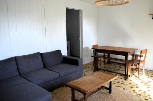 a living room with a blue couch and a table at La maison de la plage, à 350m de la mer, jardin in Asnelles