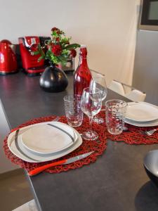 - une table avec des assiettes, des verres et une bouteille de vin dans l'établissement Au Nom de la Rose - Casa Vostra - Annemasse, à Annemasse