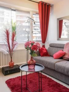 uma sala de estar com um sofá e uma mesa com flores em Au Nom de la Rose - Casa Vostra - Annemasse em Annemasse