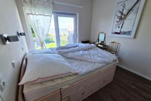 a large bed in a bedroom with a window at Haus am Merr auf Fehmarn OT Westerbergen in Albertsdorf