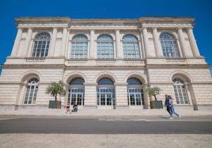a woman walking in front of a large building at Le Jardin Secret in Saint-Omer