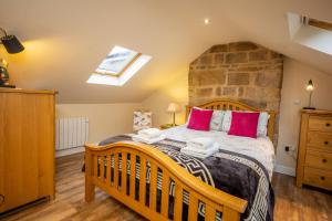 a bedroom with a large wooden bed with pink pillows at Birds Nest, Romantic getaway with stunning views in Matlock