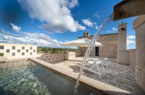 a pool with an umbrella and a table and a chair at Masseria Palombara Resort & SPA - Adults only in Manduria