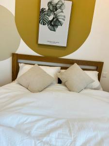 1 cama blanca con almohadas y una foto en la pared en Harmony and Deluxe Studio Subang Jaya, en Subang Jaya