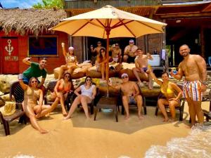 a group of people sitting under an umbrella on the beach at Hotel Prana Beach in Barú