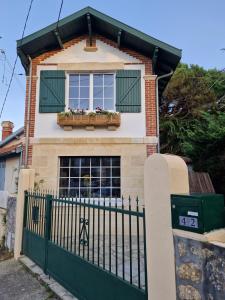 ein Haus mit einem grünen Zaun und einem Fenster in der Unterkunft Villa Bagatelle à 300m de la plage centrale, 3 chambres in Arcachon