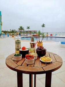 una mesa con comida y bebidas en una mesa cerca de una piscina en Golden Lake Arraial do Cabo Resort, en Arraial do Cabo