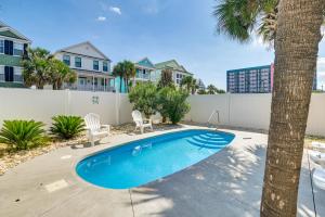 a swimming pool with two chairs and a palm tree at Surfside Beach House with Pool, Walk to Beach and Pier in Myrtle Beach